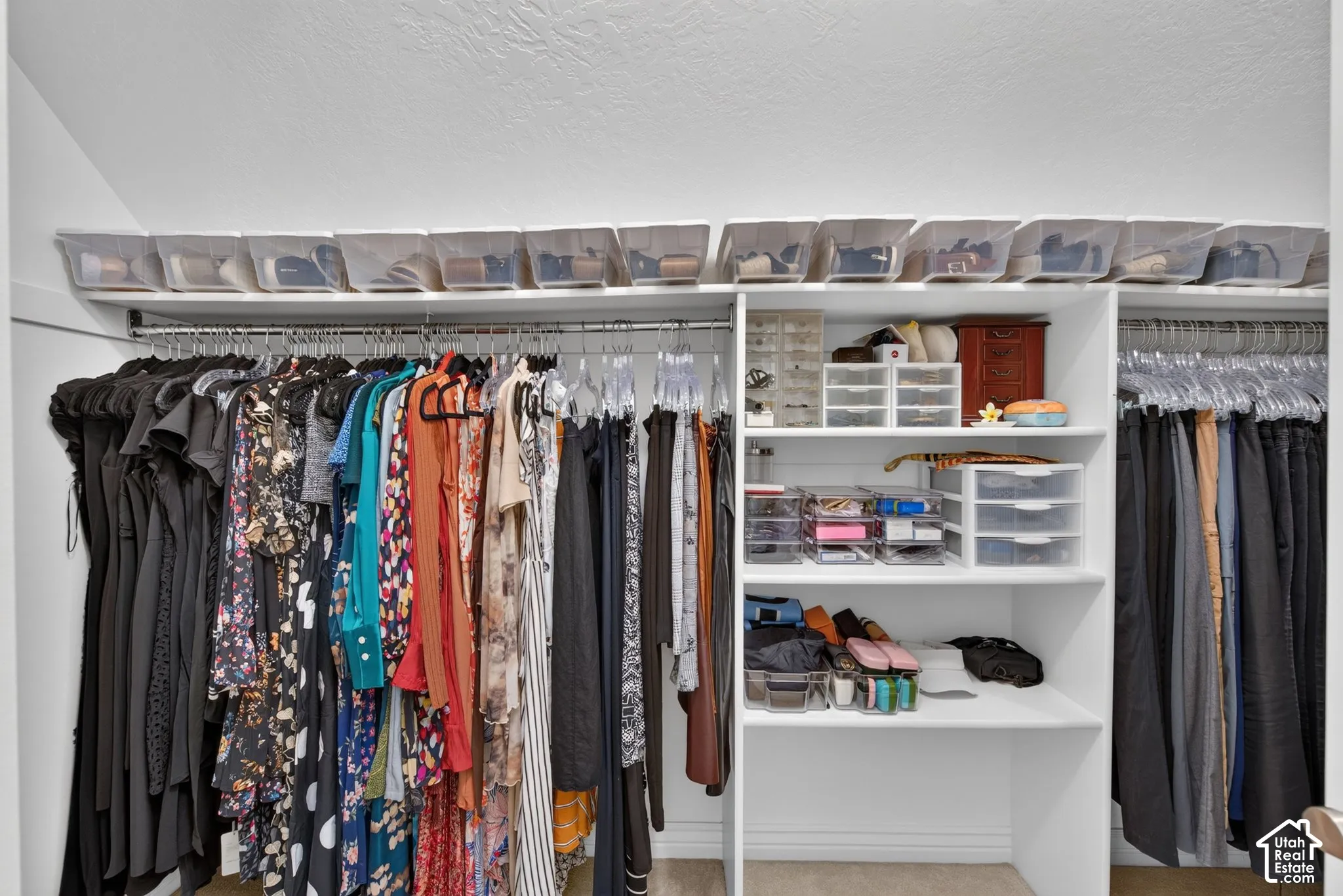 Built-in closet system featuring multiple hanging rods, white shelving, and overhead storage