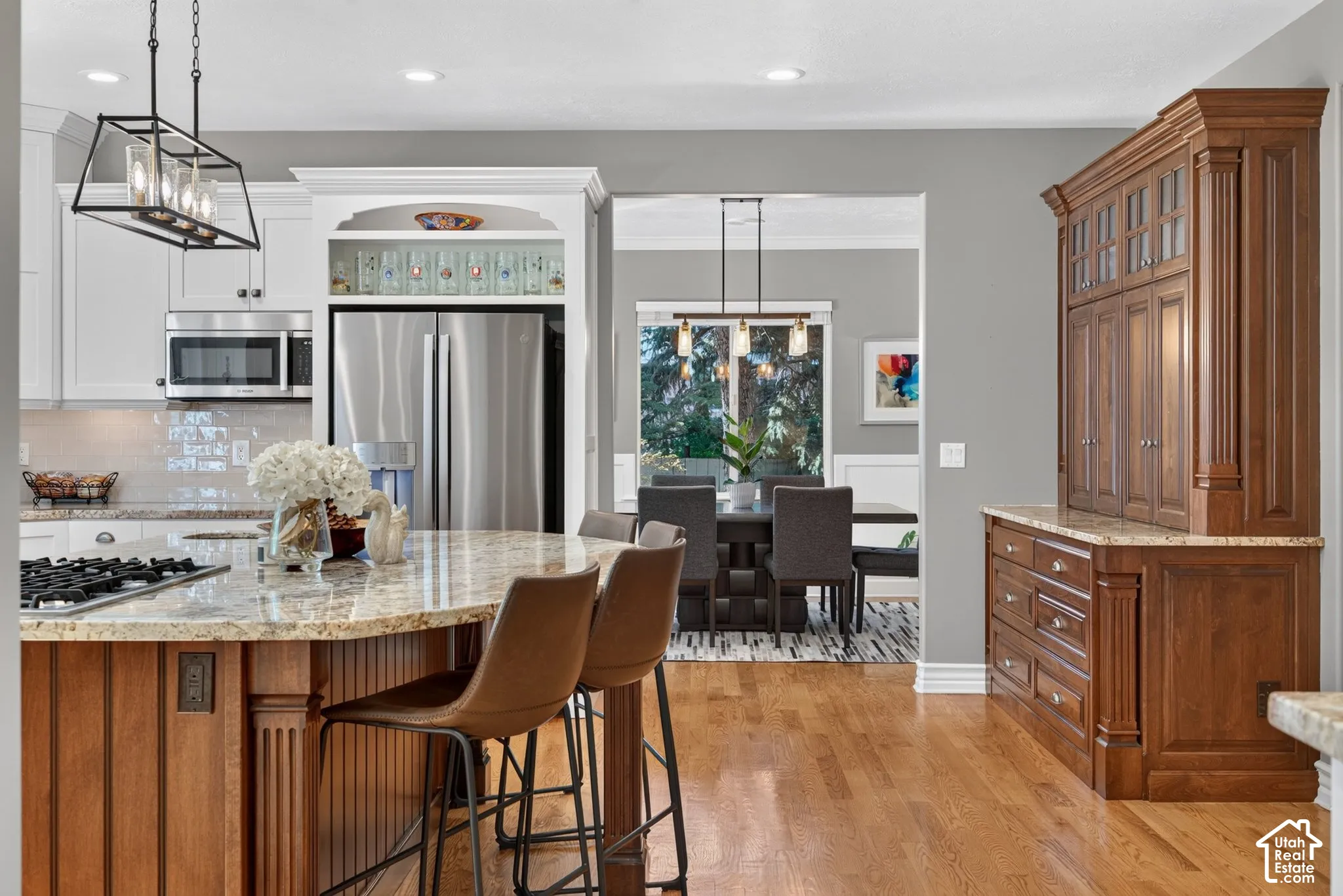 Gourmet kitchen with stainless steel appliances, granite countertops, wood-finish flooring, white cabinetry, and a built-in wood hutch