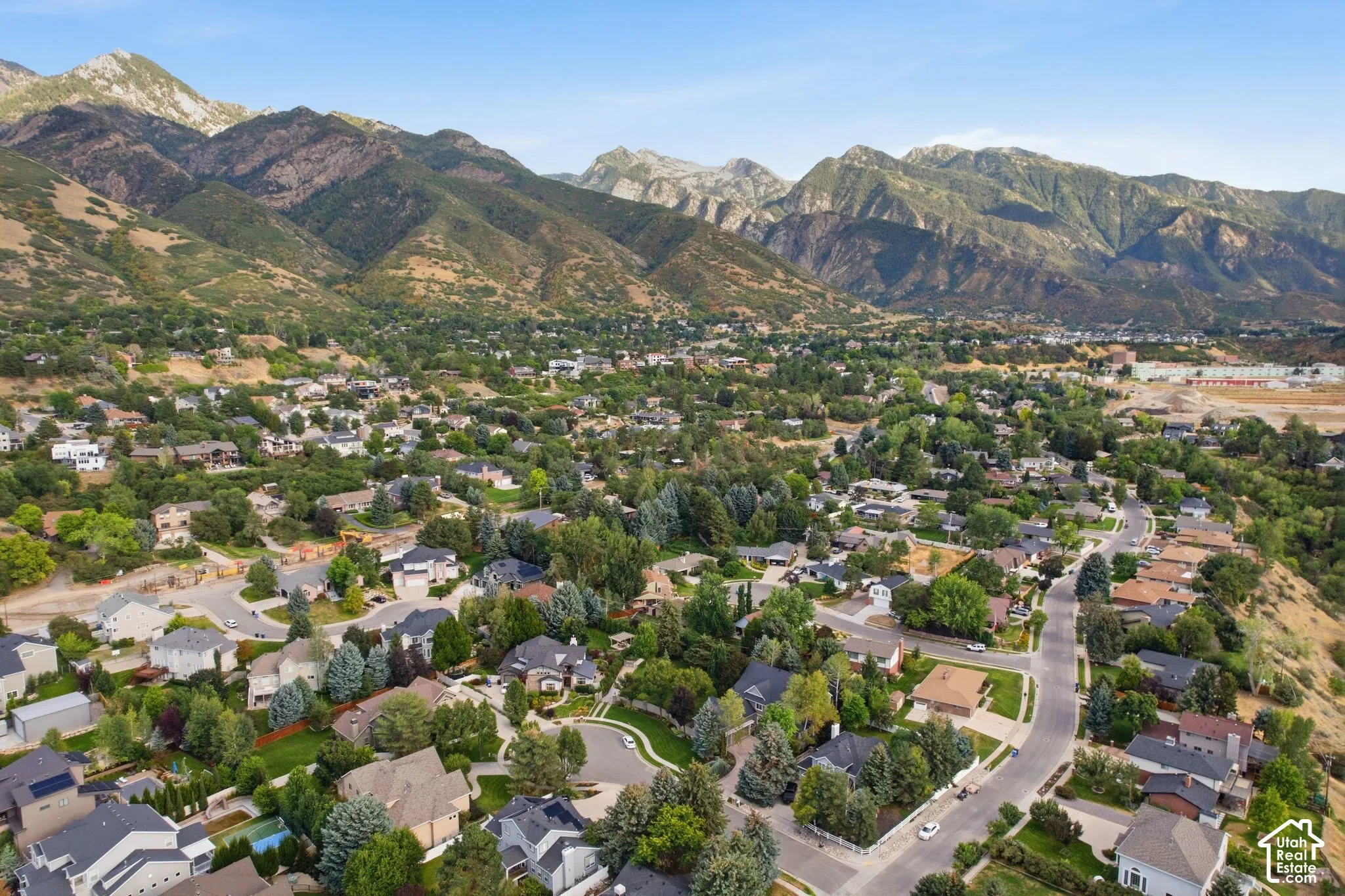 Mountainous terrain backdrop, residential community, mature trees, paved streets, varied architectural styles