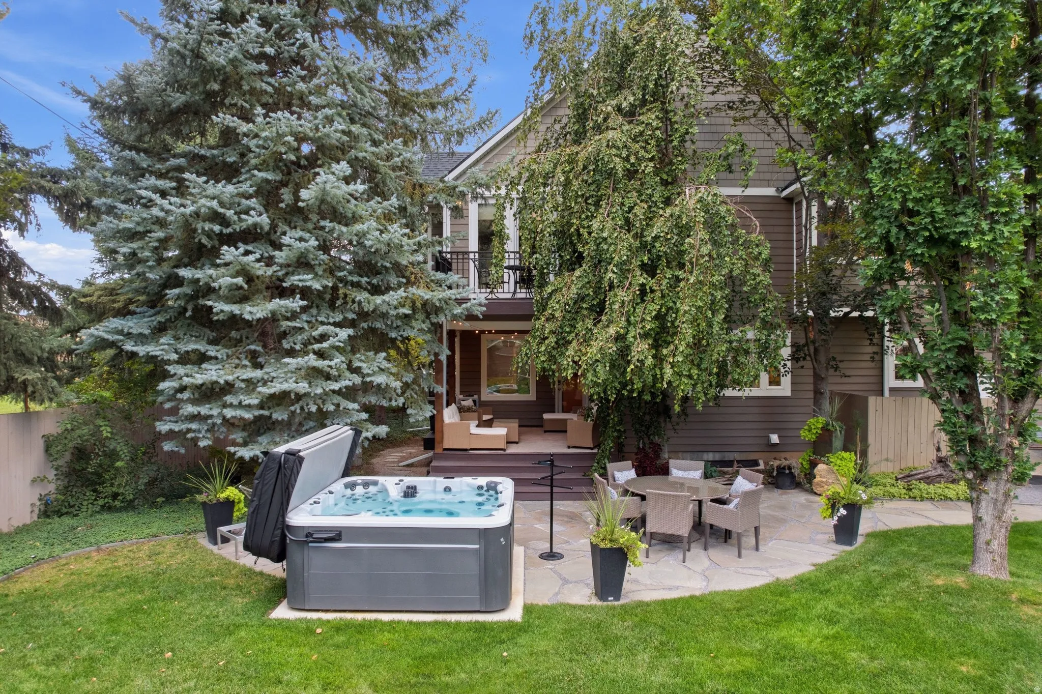 Expansive backyard featuring a hot tub, flagstone patio, and mature trees