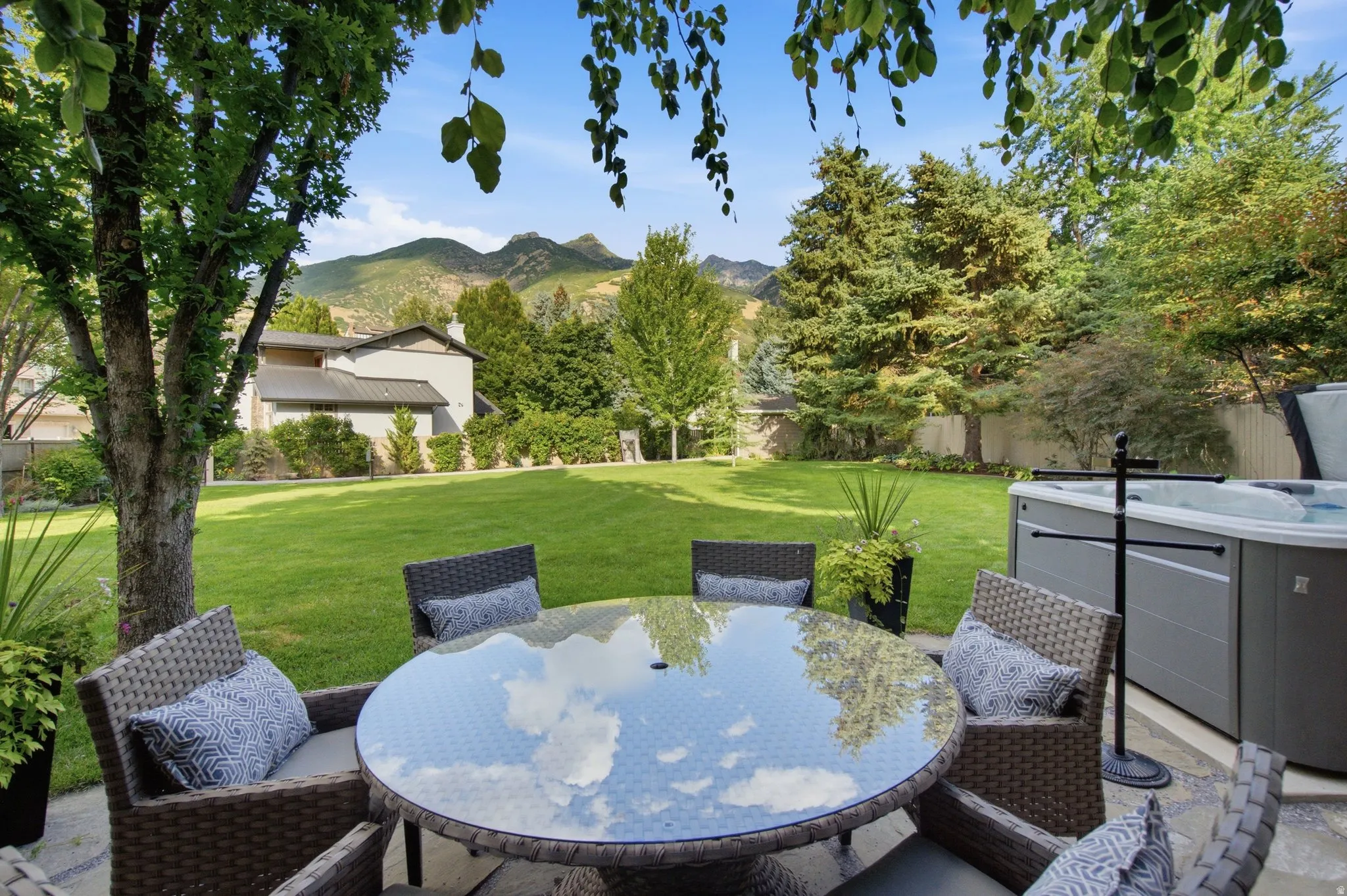 Expansive green lawn with mature trees and mountain scenery