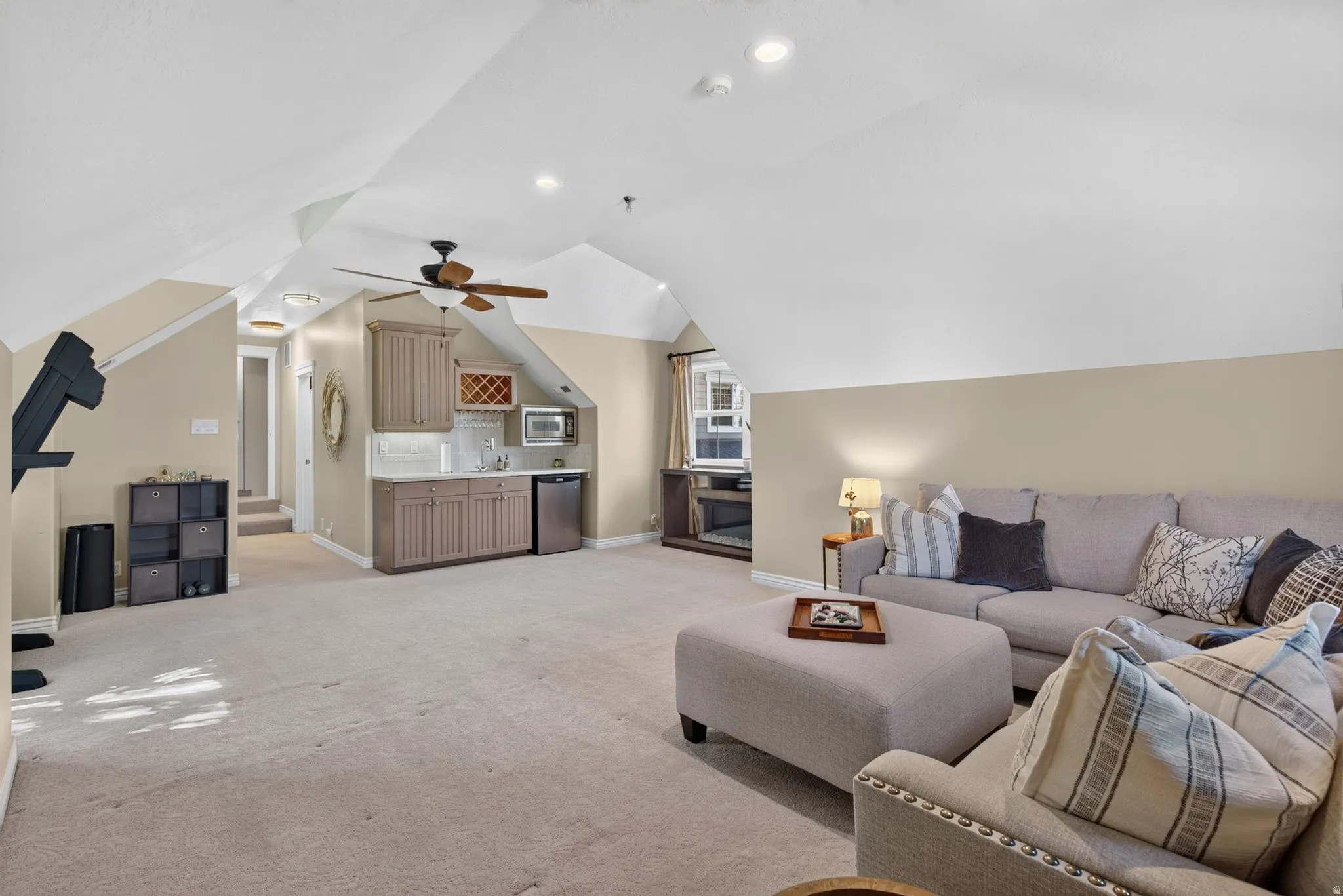 Spacious carpeted room featuring a built-in wet bar with cabinetry, recessed lighting, and a ceiling fan