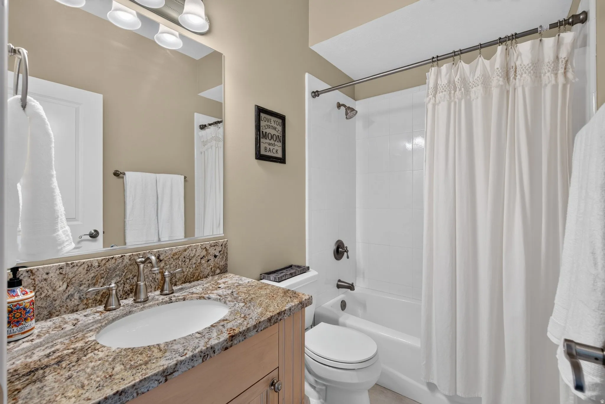 Vanity with a polished stone countertop, undermount sink, and brushed nickel faucet