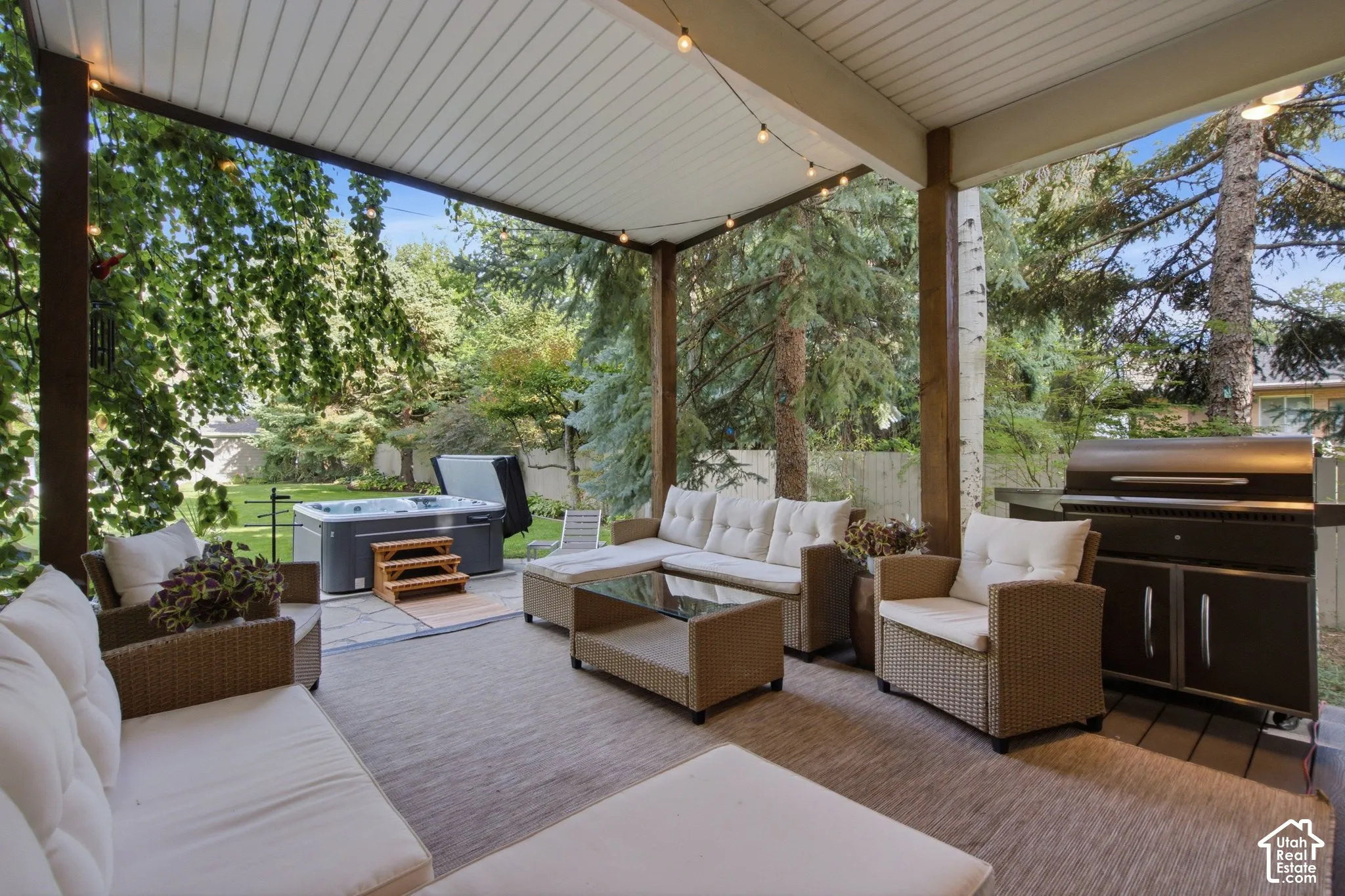 Covered patio with string lighting, a built-in grill, a hot tub, and a spacious outdoor rug