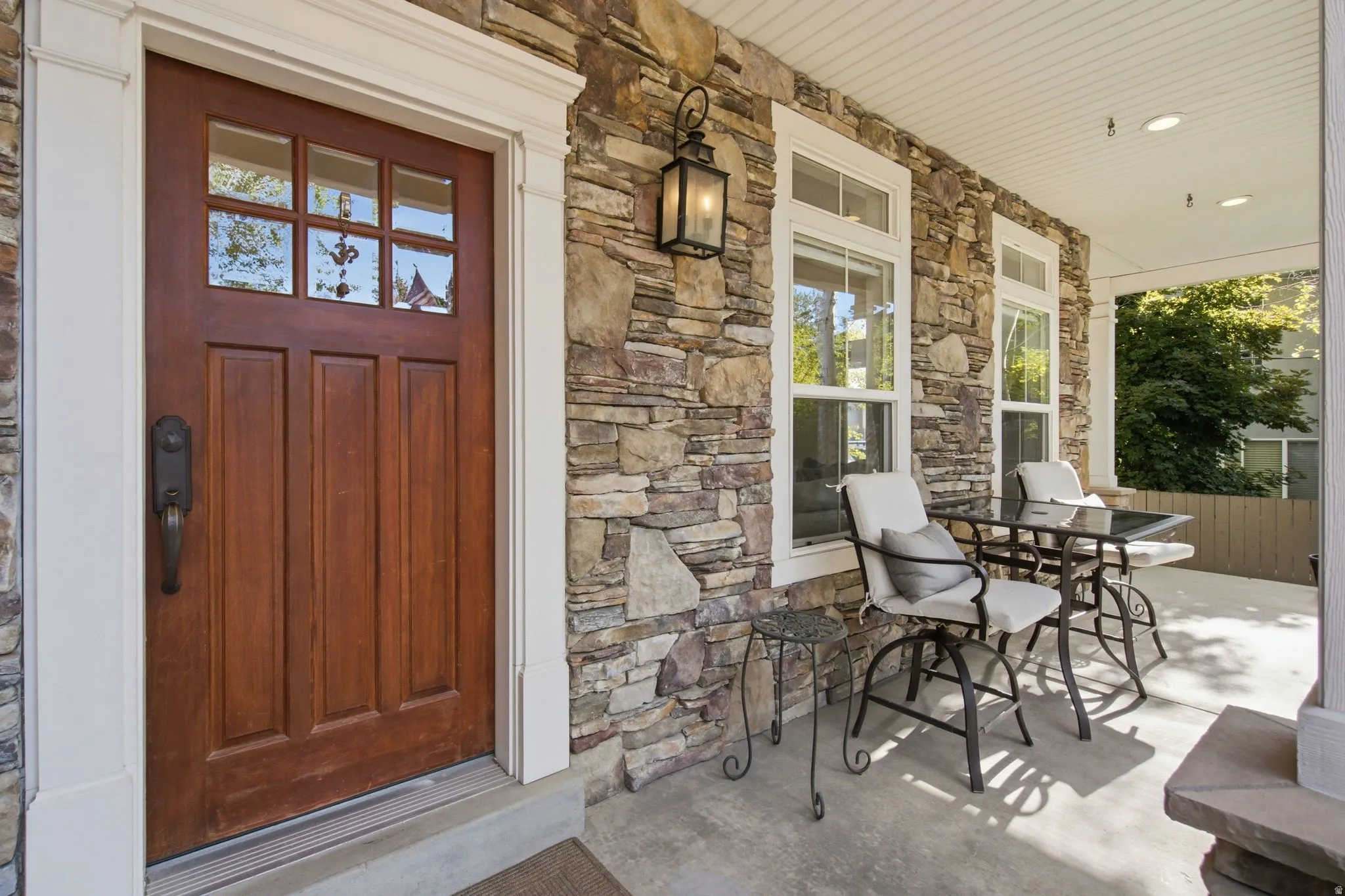 Stonework exterior with a wooden entry door featuring glass panes and white trim