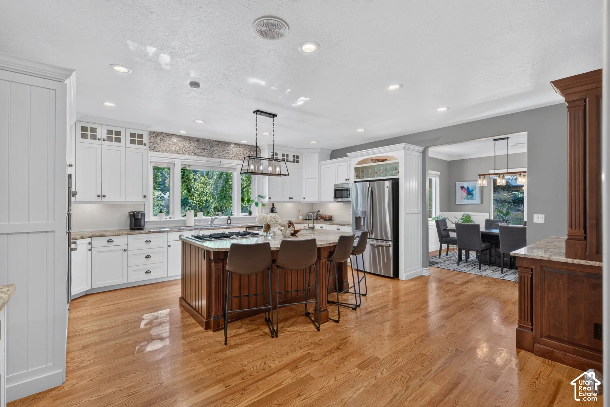 Kitchen featuring hardwood flooring, white cabinetry, a built-in stainless steel refrigerator, a center island with seating, and recessed lighting