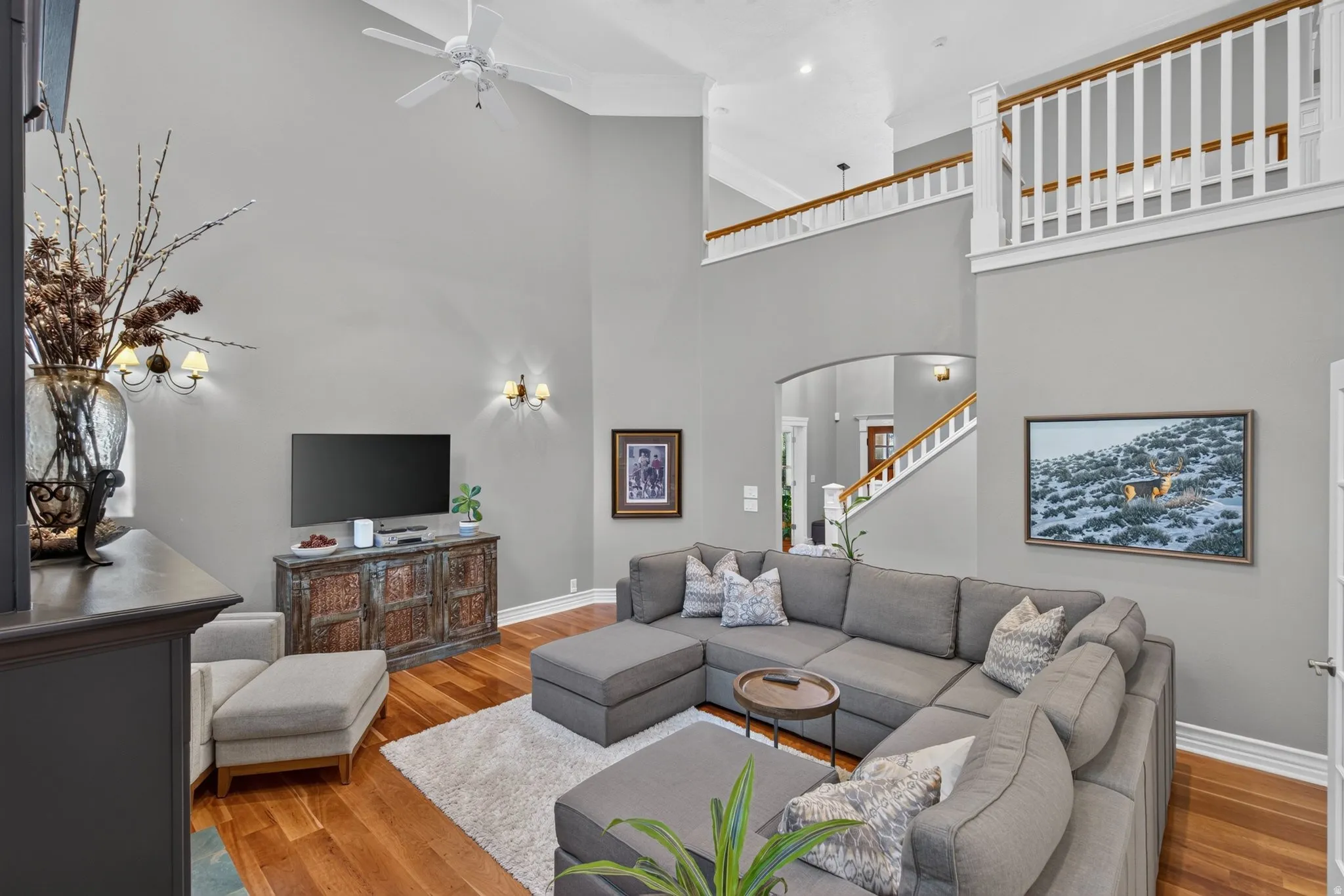 Vaulted ceiling, wood-finish flooring, white ceiling fan, staircase with wood handrail, and upper-level railing