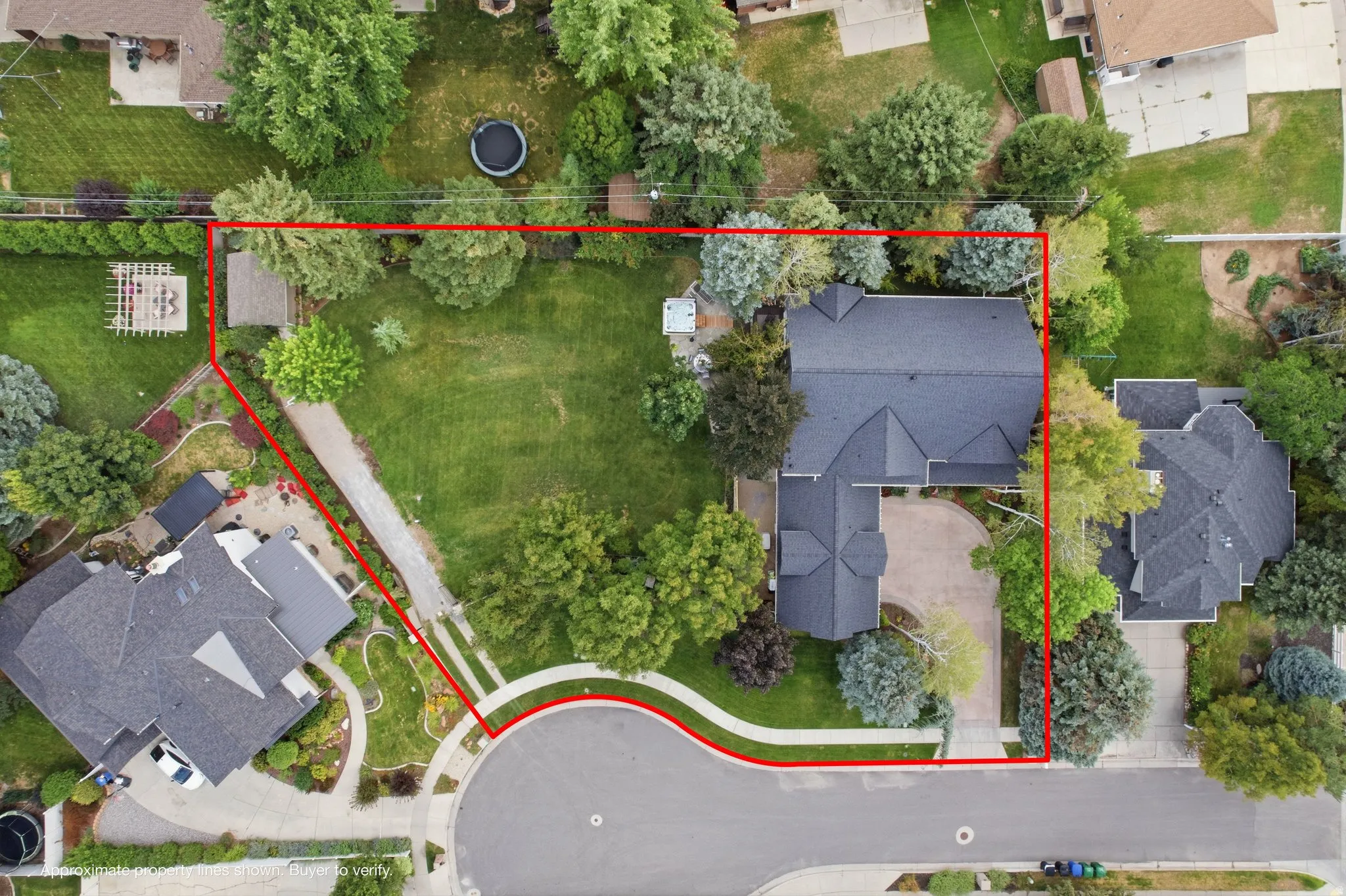 Expansive lot featuring a large residential structure with a dark shingle roof, mature landscaping, a paved driveway, and a cul-de-sac frontage