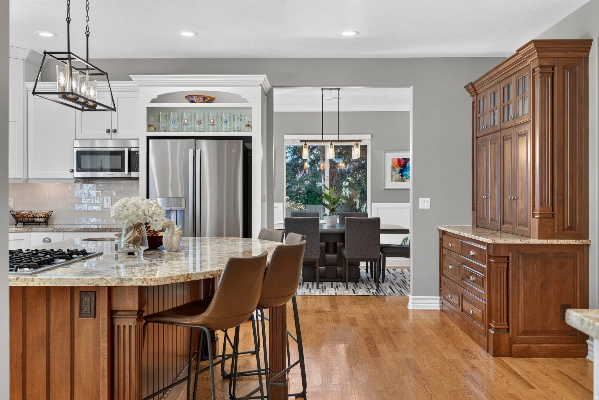 Gourmet kitchen with stainless steel appliances, granite countertops, wood-finish flooring, white cabinetry, and a built-in wood hutch