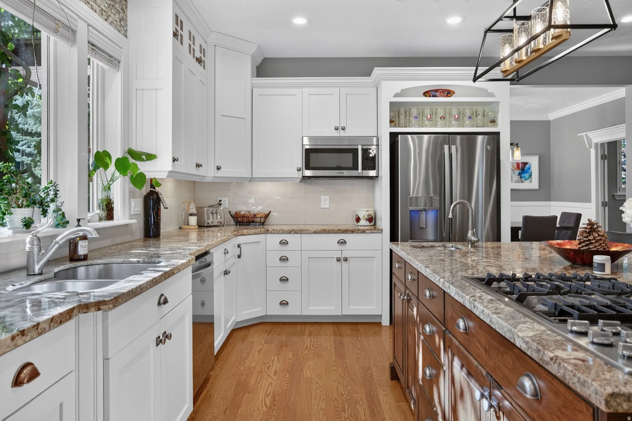 White shaker cabinetry, stainless steel appliances, granite countertops, wood-finish flooring, and a built-in gas range