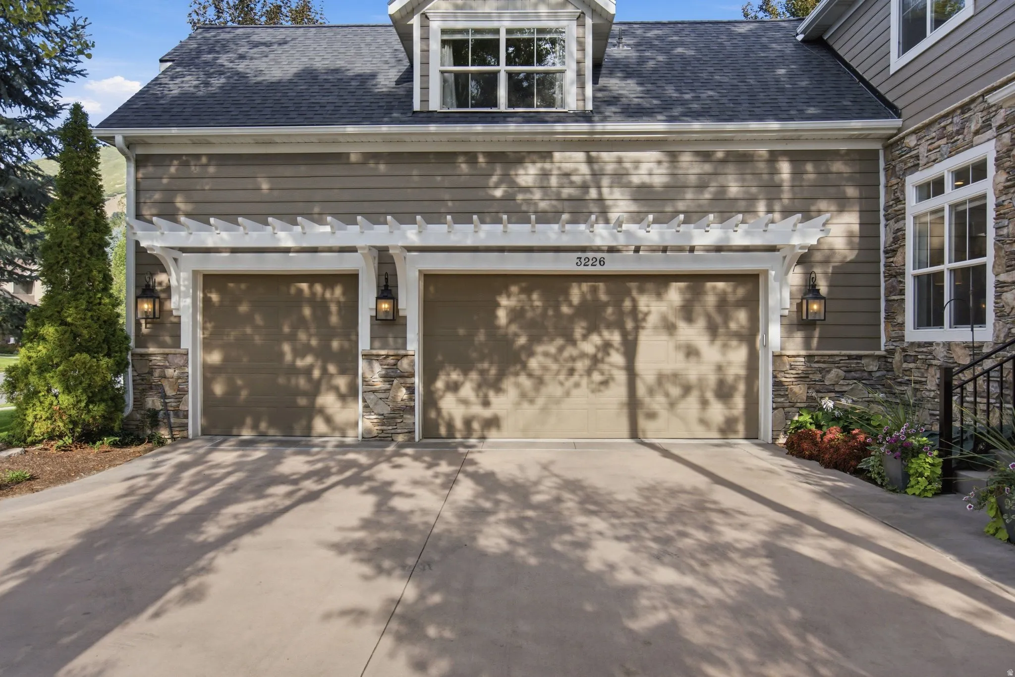 Two-car garage with individual doors, accented by stone veneer columns and a white pergola-style overhang