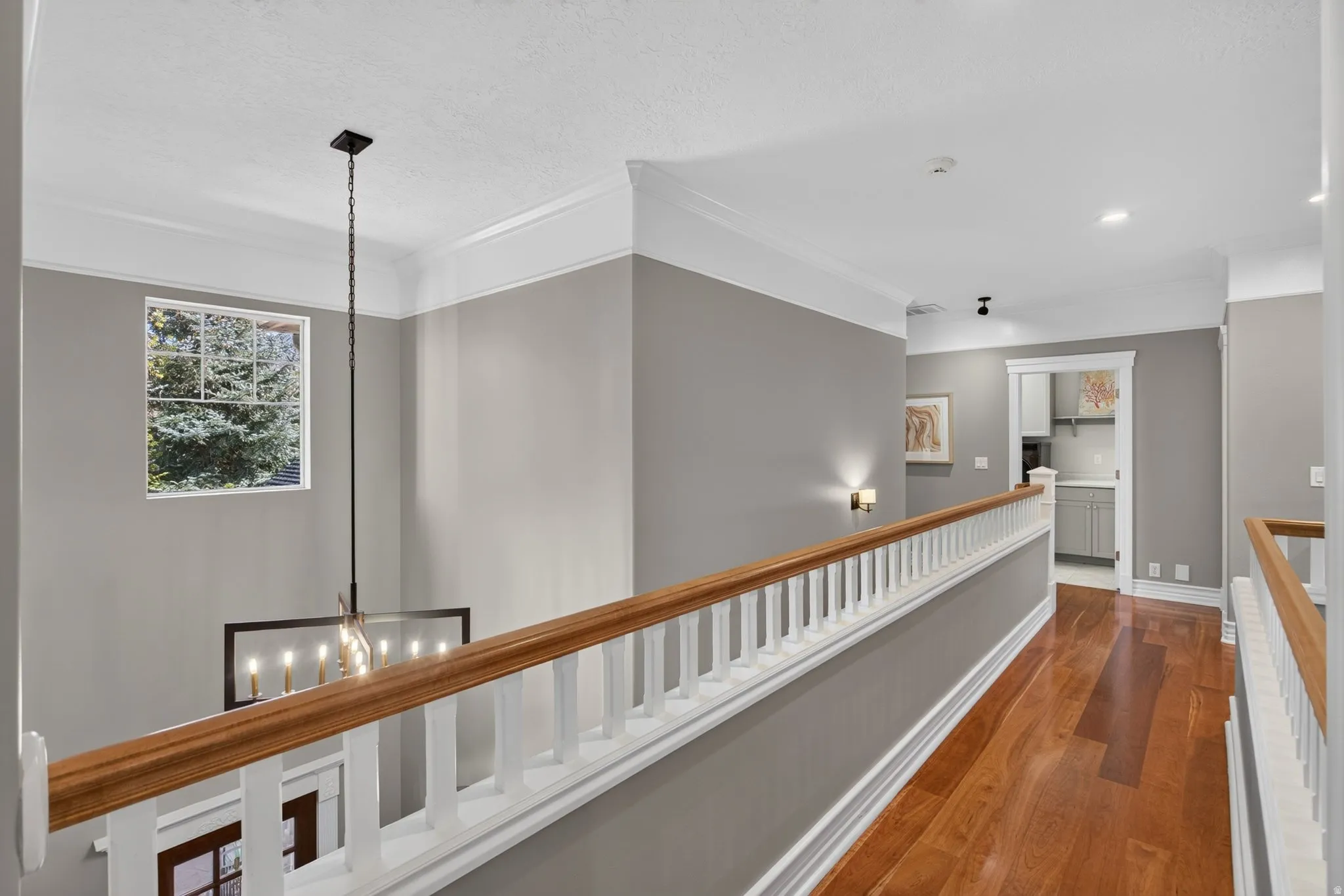 Hardwood flooring and crown molding throughout the hallway