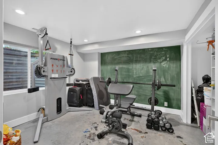 Recessed lighting, chalkboard accent wall, window, and concrete flooring