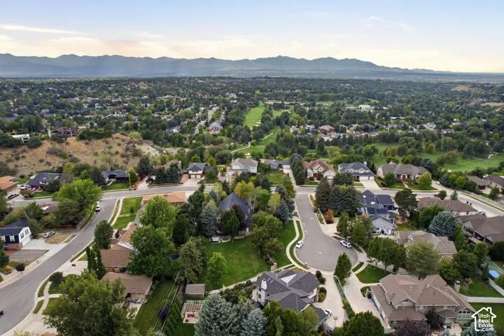 Expansive residential area with mature tree coverage, mountain backdrop, and golf course terrain