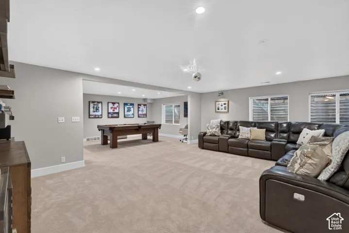 Recessed lighting illuminates the expansive carpeted flooring, complemented by multiple wall-mounted windows