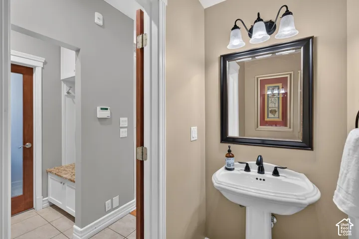 Pedestal sink with black faucet, framed mirror, and three-light vanity fixture