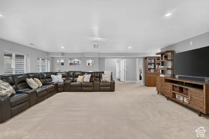 Recessed lighting, built-in shelving, and neutral wall tones enhance this expansive carpeted space