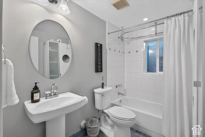 Pedestal sink with a chrome faucet, oval mirror, white subway tile shower surround with accent tiles, and a built-in window