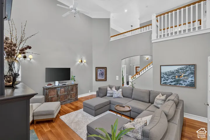 Vaulted ceiling, wood-finish flooring, white ceiling fan, staircase with wood handrail, and upper-level railing