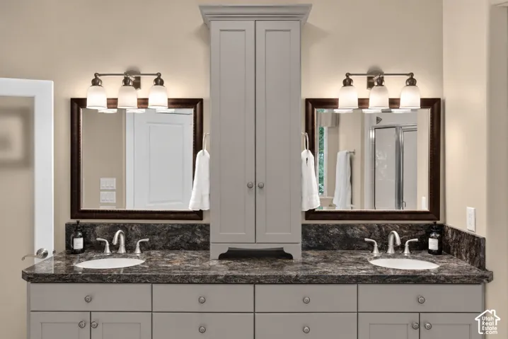 Dual vanity with undermount sinks, gray cabinetry, and a dark stone-finish countertop