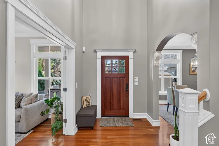Rich wood-finish flooring, a solid wood entry door with glass panes, and decorative trim work