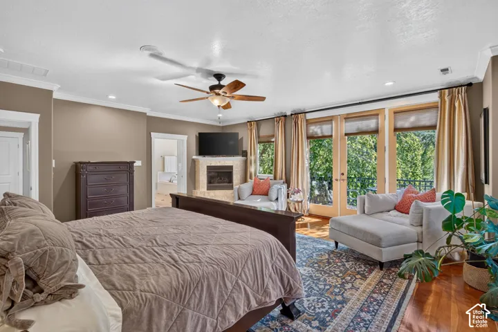 Hardwood flooring, ceiling fan, crown molding, double French doors with transom windows, and a built-in fireplace with stone surround