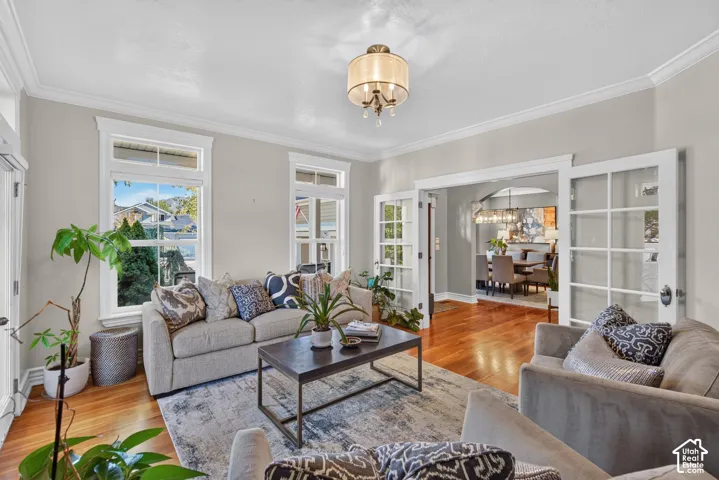 Hardwood flooring, crown molding, French doors, recessed lighting, and a decorative chandelier
