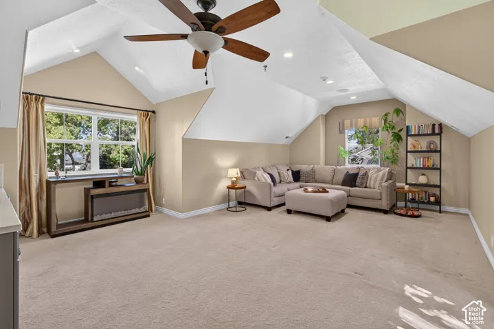 Spacious attic room with vaulted ceilings, ceiling fan, and recessed lighting