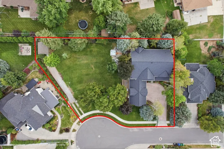 Expansive lot featuring a large residential structure with a dark shingle roof, mature landscaping, a paved driveway, and a cul-de-sac frontage