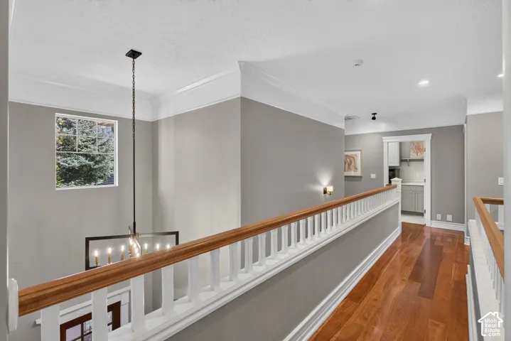 Hardwood flooring and crown molding throughout the hallway