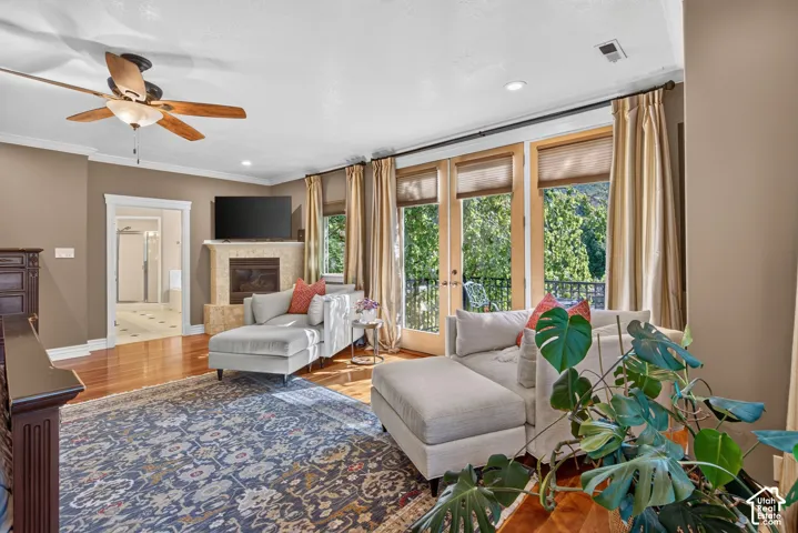 Hardwood flooring throughout, a ceiling fan with integrated lighting, and a stone-clad fireplace