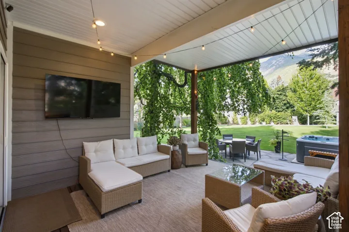 Covered patio featuring an outdoor television, string lighting, and a built-in hot tub