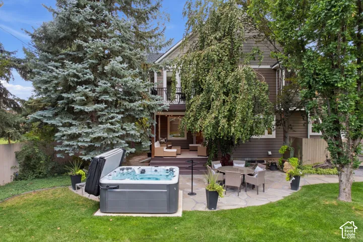 Expansive backyard featuring a hot tub, flagstone patio, and mature trees