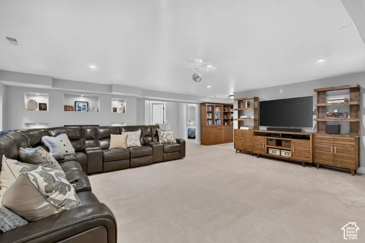 Recessed wall niches with integrated lighting, built-in media console with open shelving, and light-toned carpeting