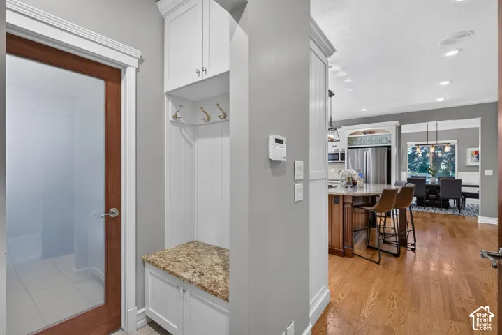 Built-in mudroom bench with granite countertop, white cabinetry, and wall hooks