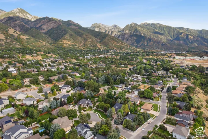 Mountainous terrain backdrop, residential community, mature trees, paved streets, varied architectural styles