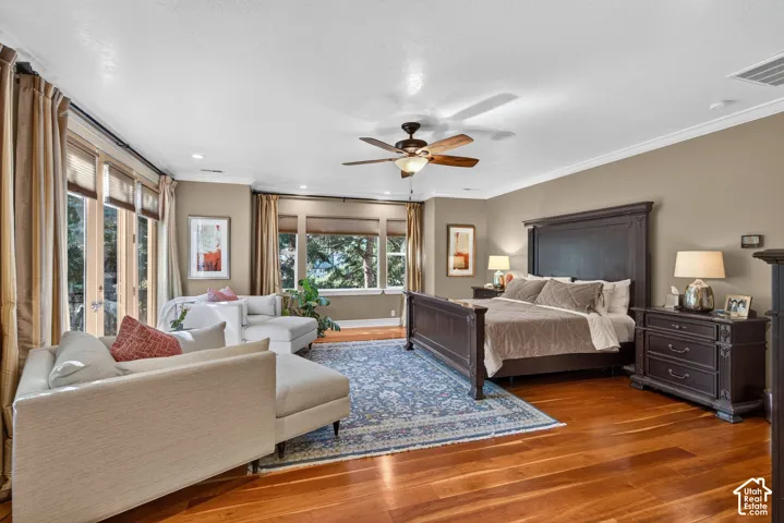 Hardwood flooring, crown molding, ceiling fan, and multiple windows