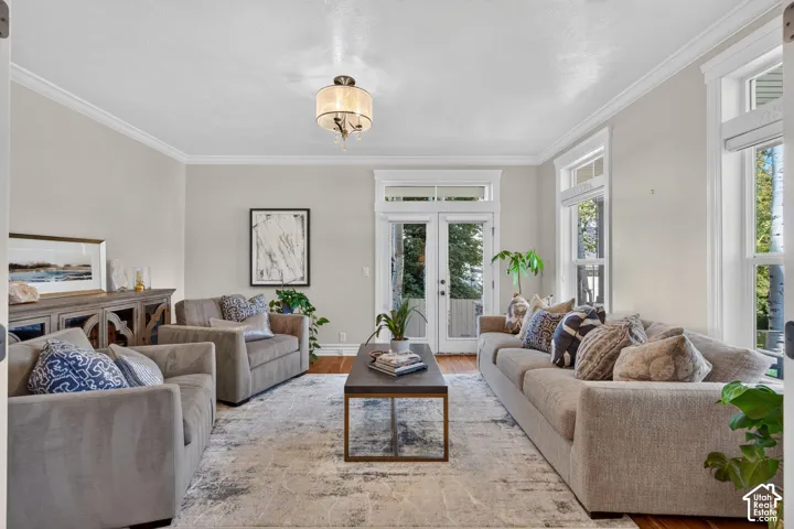 Hardwood flooring, crown molding, double French doors, large windows, and a chandelier with a drum shade