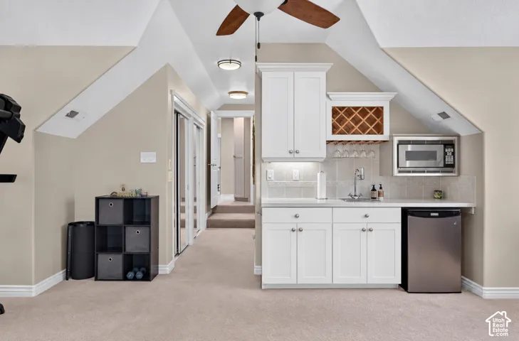 Built-in wet bar with white cabinetry, stainless steel sink, and integrated wine rack