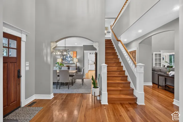 Hardwood flooring throughout, a grand staircase with white balusters, and arched doorways define this entry