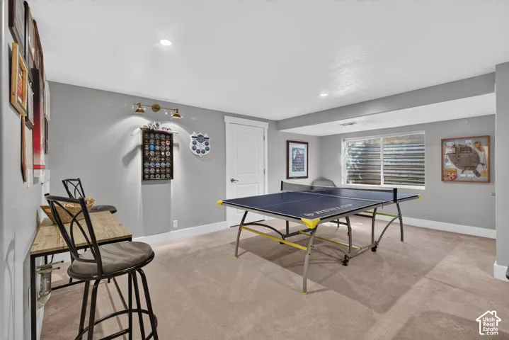 Recessed lighting, wall-mounted fixtures, window with blinds, light gray wall paint, and light-colored carpeting