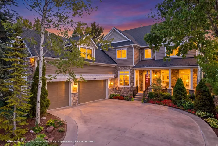 Stone and siding exterior with a covered front porch, integrated two-car garage, and a curved concrete driveway