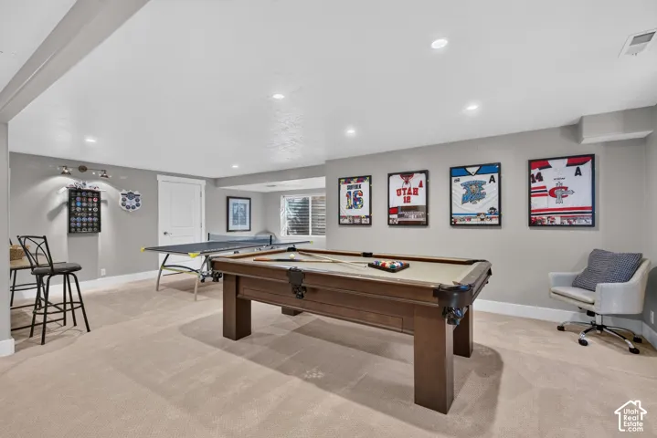 Recessed lighting illuminating the entertainment space with light gray walls, white trim, and light-toned carpeting