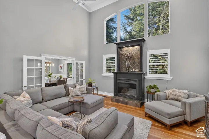 Two-story ceiling, hardwood flooring, fireplace with a tiled surround, arched windows, and French doors