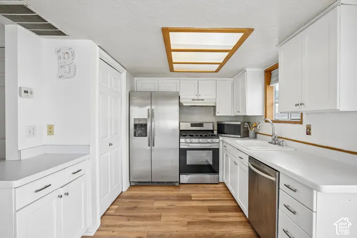 White cabinetry and countertops with wood-finish flooring
