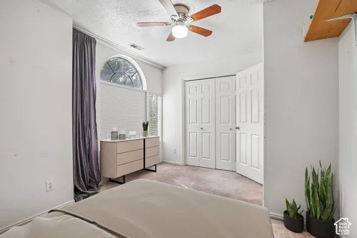 Arched window with blinds, ceiling fan with light fixture, and paneled bifold closet doors