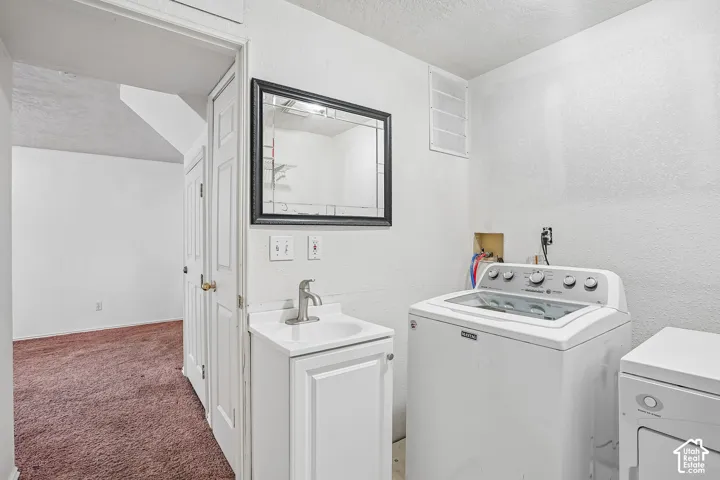 Utility area featuring a sink with a chrome faucet, a base cabinet, and a framed mirror