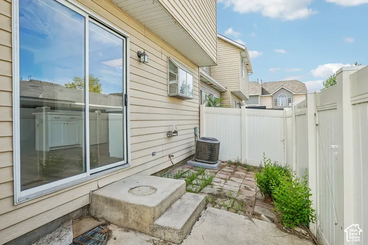 Sliding glass patio door, concrete patio, vinyl siding, privacy fencing, and an outdoor wall-mounted light fixture