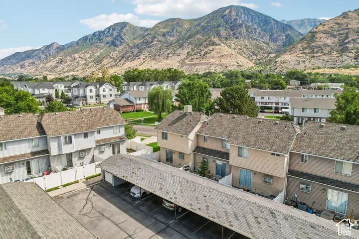Townhome community with mountain backdrop, featuring a covered parking structure, private patios, and mature landscaping