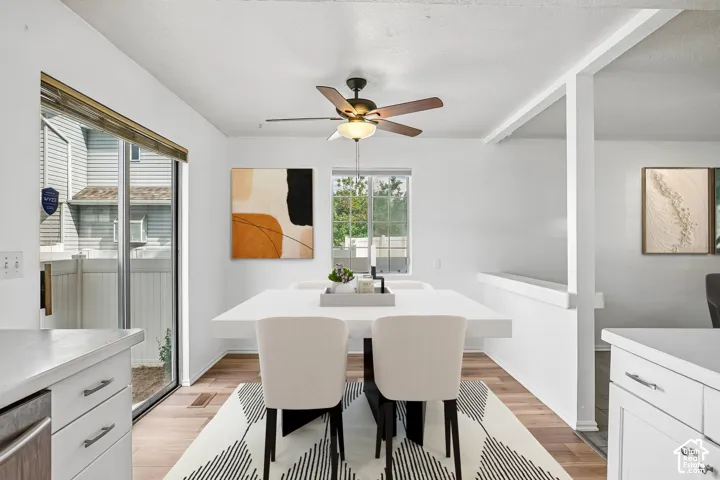 Wood-finish flooring throughout, white cabinetry with silver hardware, sliding glass door, and a ceiling fan with integrated lighting